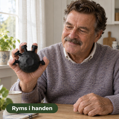 Äldre man vid ett köksbord håller en svart silikonboll med fingrarna på knapparna, med texten ryms i handen