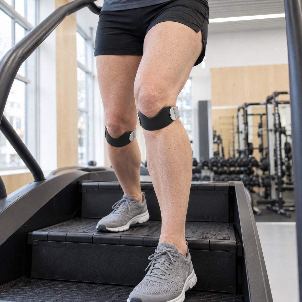 Ben på en stegmaskin i ett gym med knärem under knäskålen på båda knäna