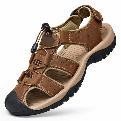 Brun promenadsandal med kardborreband på hälen och elastisk snörning, sedd snett framifrån mot vit bakgrund