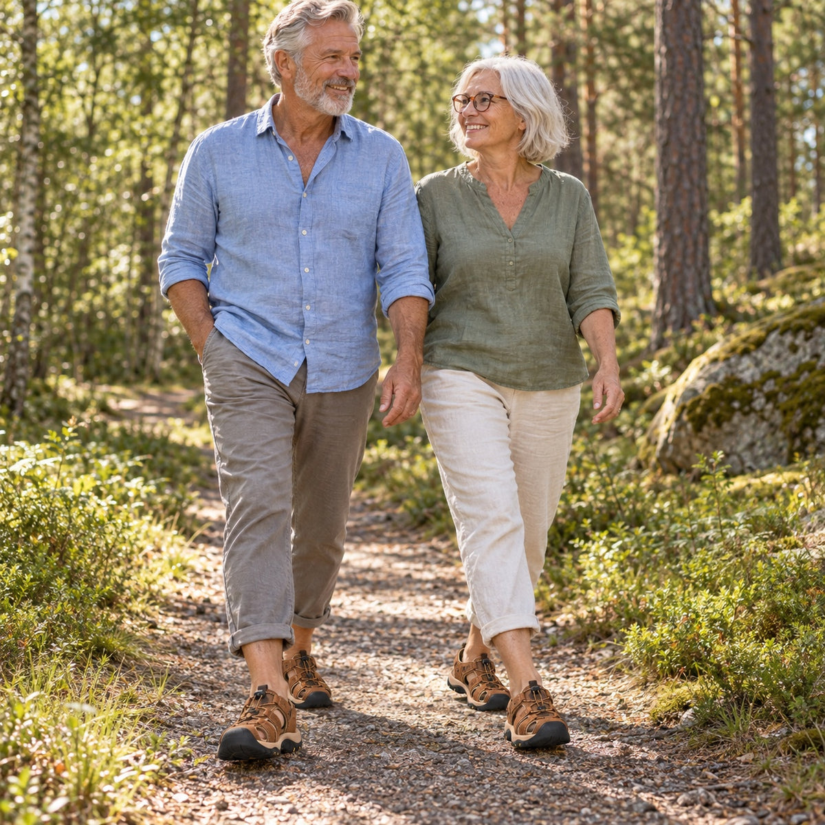 Ett par går på en skogsstig i solljus och bär bruna promenadsandaler