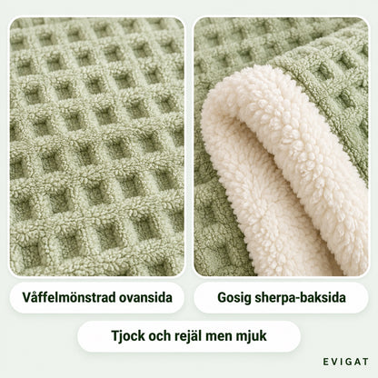 Närbild på plädets våffelmönstrade ovansida och den vita sherpa-baksidan, med texterna våffelmönstrad ovansida, gosig sherpa-baksida och tjock och rejäl men mjuk