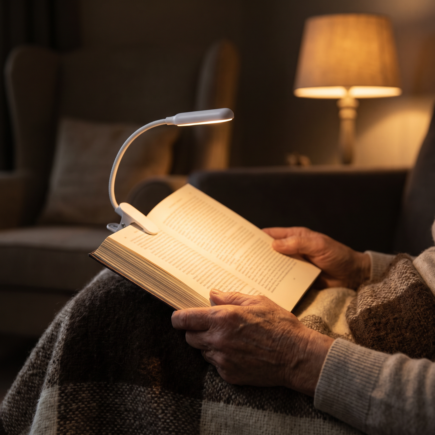 Klämlampa som lyser upp en bok i en fåtölj på kvällen
